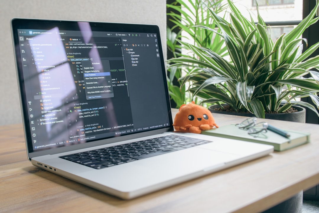 Laptop displaying code with a small plush toy.