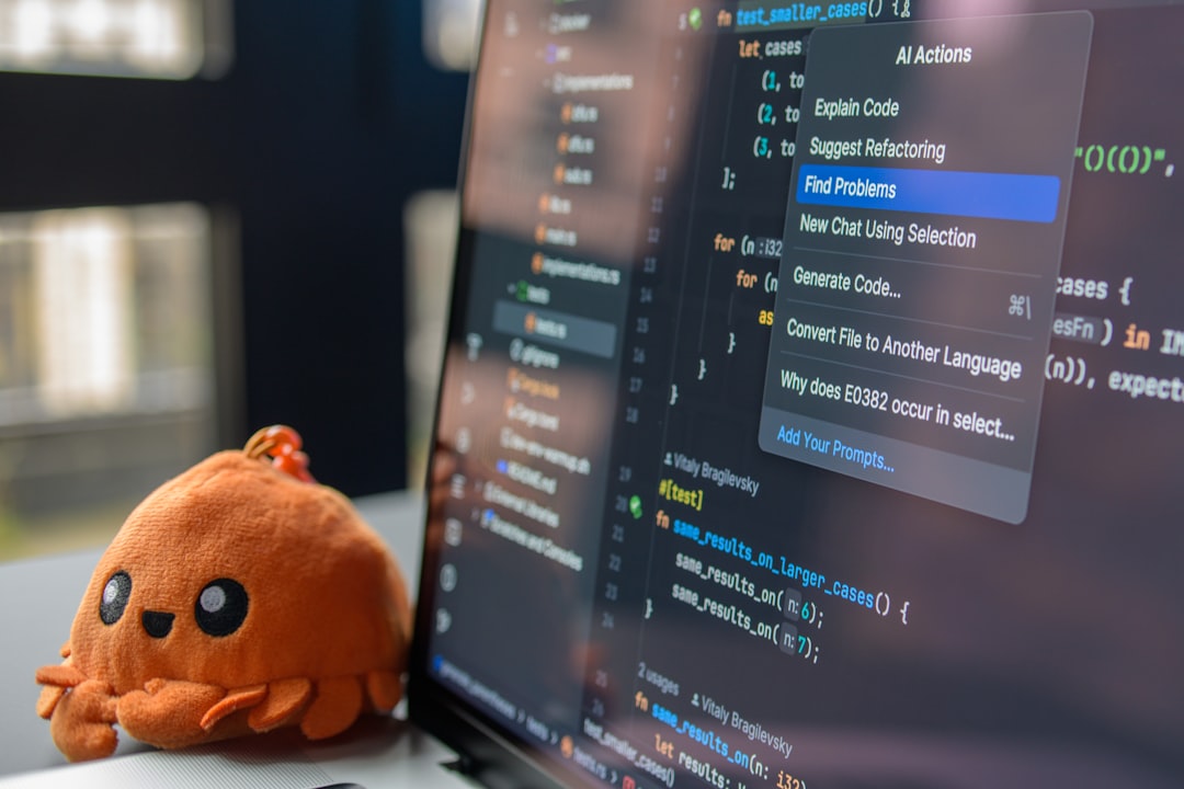 A cute octopus toy sits beside a laptop displaying code.
